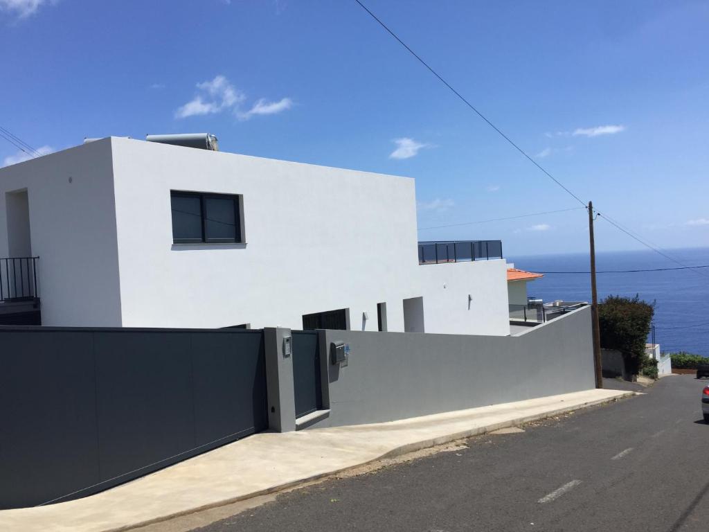a white house with a black gate at Calheta Ocean View Apartments 1 in Estreito da Calheta