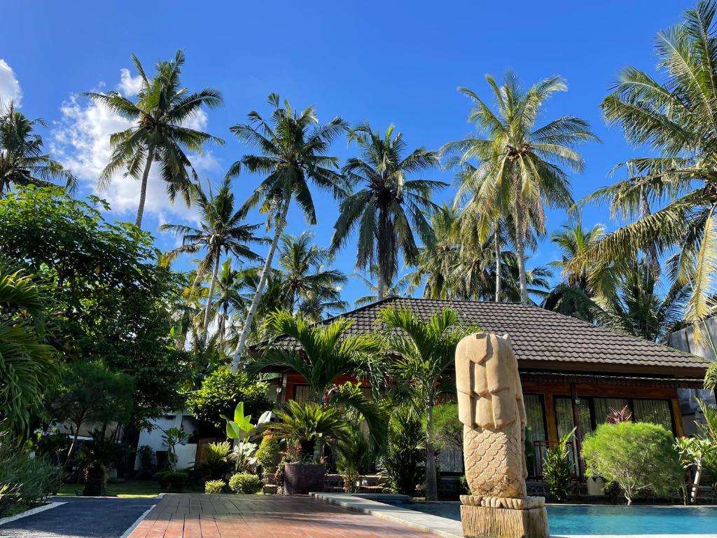 un complexe avec une statue en face d'une piscine dans l'établissement Red island villas, à Banyuwangi