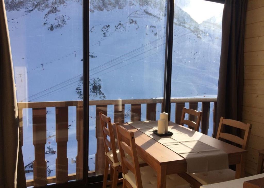 einen Holztisch mit Stühlen und ein großes Fenster in der Unterkunft Vue panoramique - 4pers - parking in La Mongie