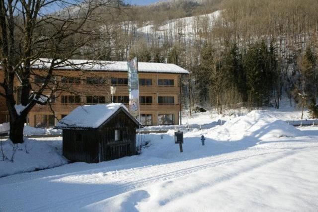 ein Gebäude im Schnee vor einer Straße in der Unterkunft Haus Kanisblick Appartements in Schnepfau