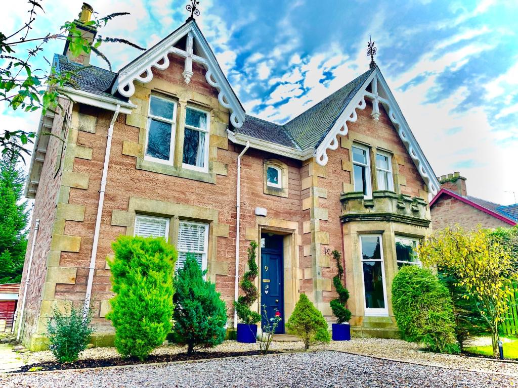una vieja casa de ladrillo con una puerta azul en Ladies Lodge Inverness en Inverness