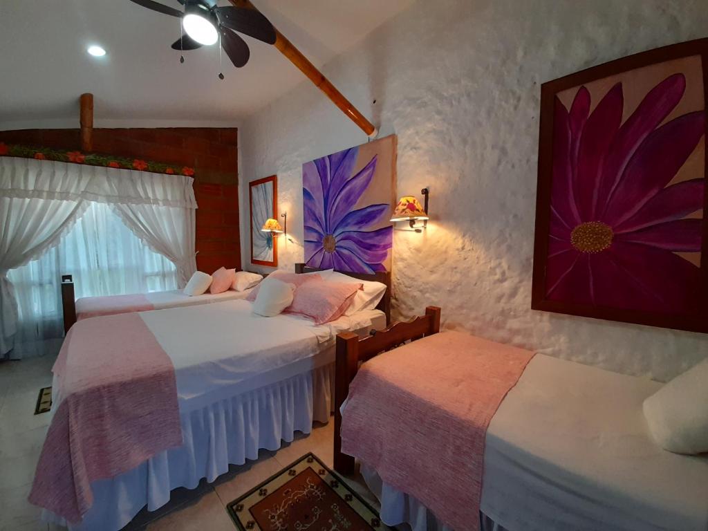 a bedroom with two beds and a painting on the wall at Villa Luzandi in Quimbaya