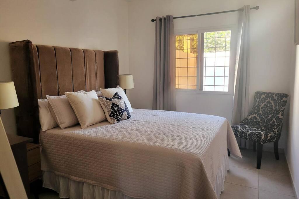 a bedroom with a bed and a window and a chair at Linda, cerca de todo, parqueo, patio, netflix in La Ceiba