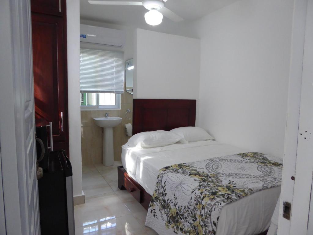 um quarto com uma cama e uma casa de banho com um lavatório em Cozy Studios-Private Entrance- HS Internet-AC-Hot Water-Backup Generator-near the Beach em San Felipe de Puerto Plata