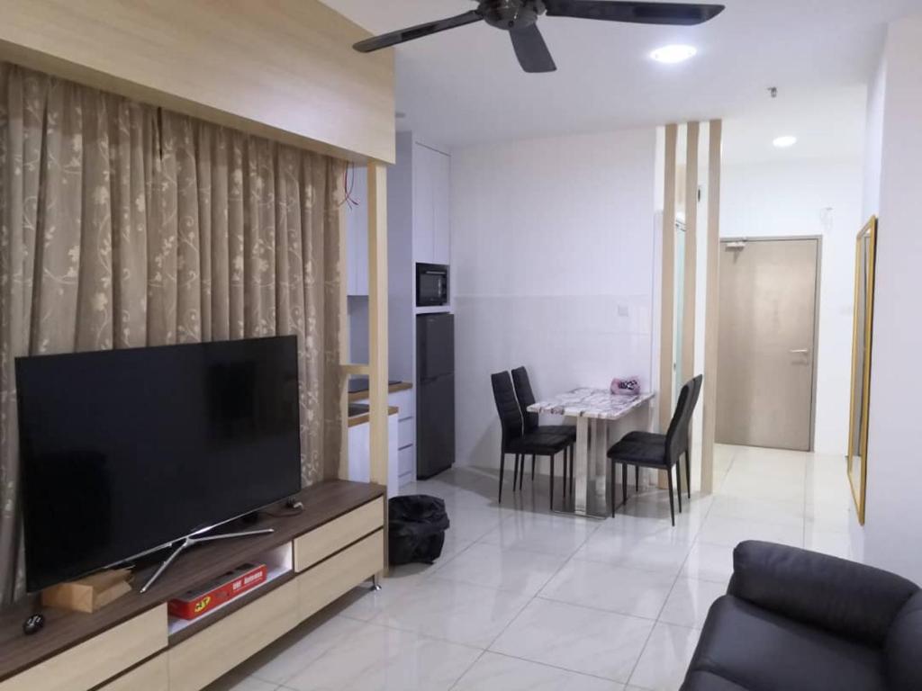 a living room with a television and a table with chairs at Era Amazing Manhattan Suite in Penampang
