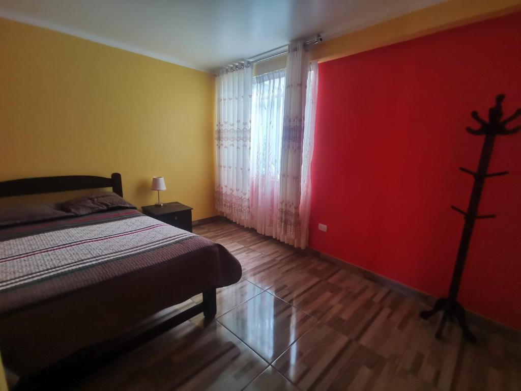 1 dormitorio con cama y pared roja en Apartamento Hogareño con 3 dormitorios, en Huancayo