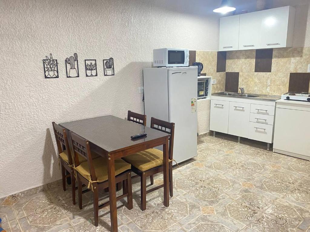 cocina con mesa, sillas y nevera en Departamentos - del TALAMPAYA en Villa Unión