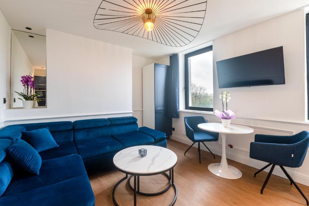 - un salon avec un canapé bleu et une table dans l'établissement Studios Le Medicis vue Seine, à Belbeuf