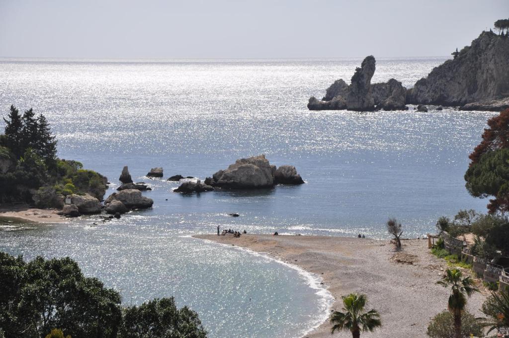 a beach with people on the sand and rocks in the water at Taormina Mare Appartamento 300 Metri dal Mare in Giardini Naxos