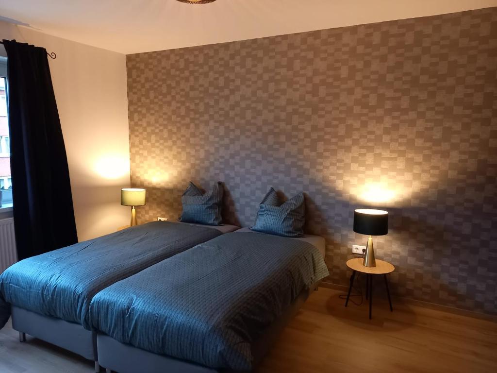 a bedroom with a bed with blue sheets and two lamps at Ems Apartment in Emden