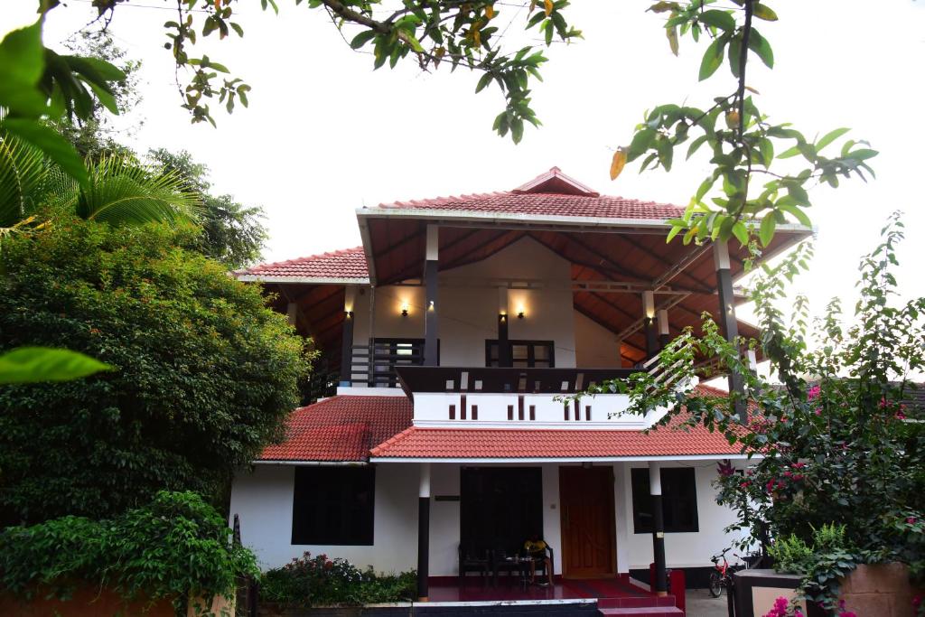 Casa blanca con balcón y árboles en Nivaasana Bed & Breakfast en Kalpatta