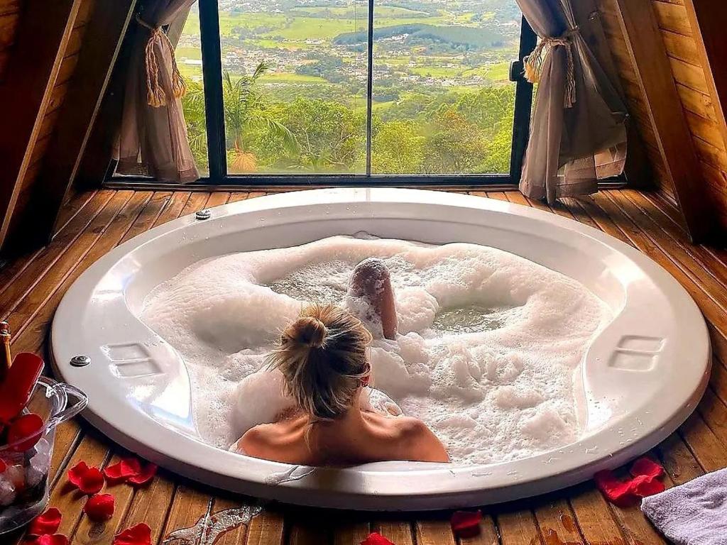 una mujer tumbada en una bañera delante de una ventana en Amore cabana, en Santo Amaro da Imperatriz