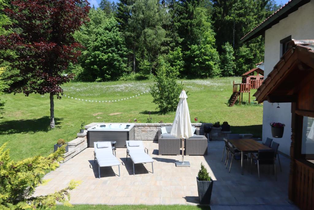 um pátio com um guarda-sol, uma mesa e cadeiras em Apartment am Nationalpark Bayerwald em Lindberg