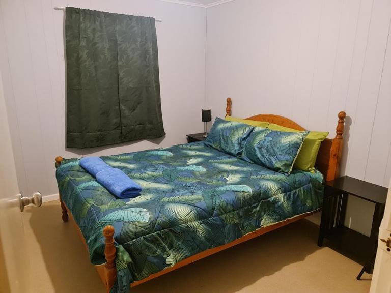 a bedroom with a bed with blue sheets and a window at City Centre Apartments in Coober Pedy