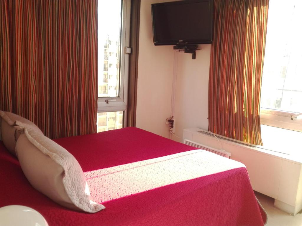 1 dormitorio con 1 cama con manta roja y ventana en Esmeralda Vista en Buenos Aires