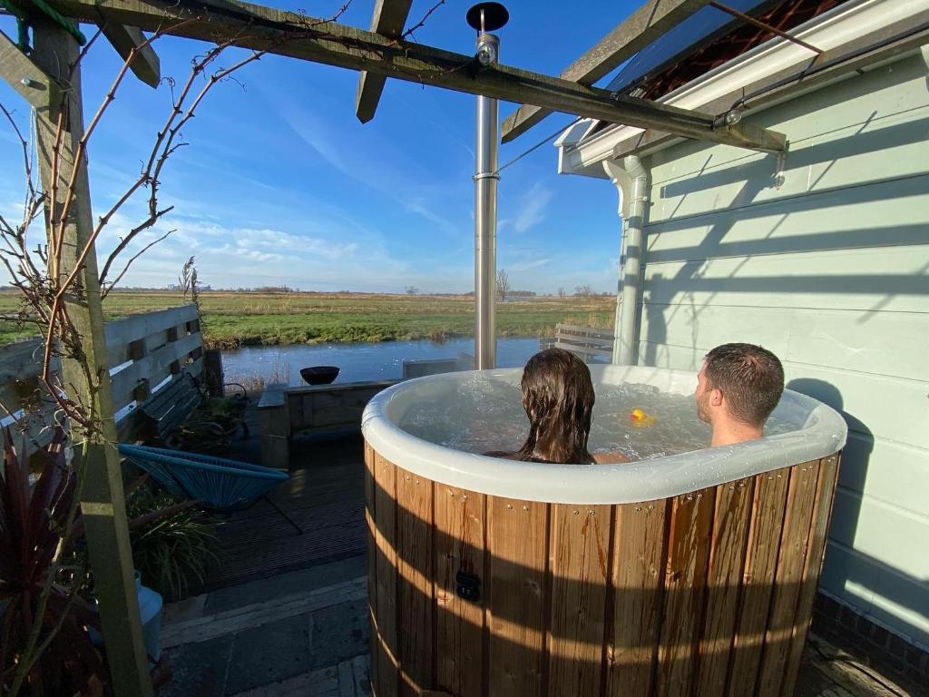 a man and a woman sitting in a hot tub at Romantic Dutch hideaway in Jisp