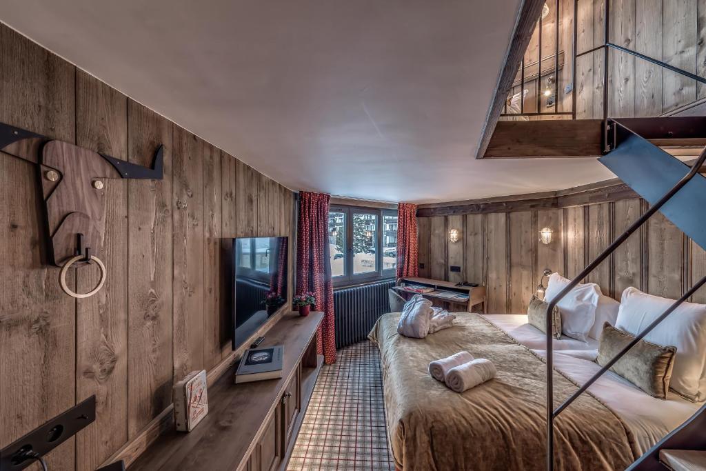 a bedroom with wooden walls and a bed and a television at HOTEL LE VAL D&#39;ISERE in Val-d&#39;Isère