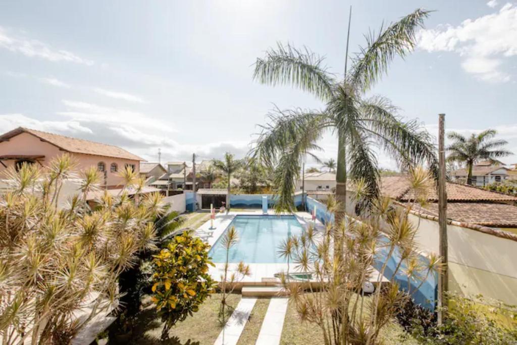 una piscina con una palmera al lado de un edificio en Casa Maravilhosa Unamar Verão Vermelho Cabo Frio, en Tamoios