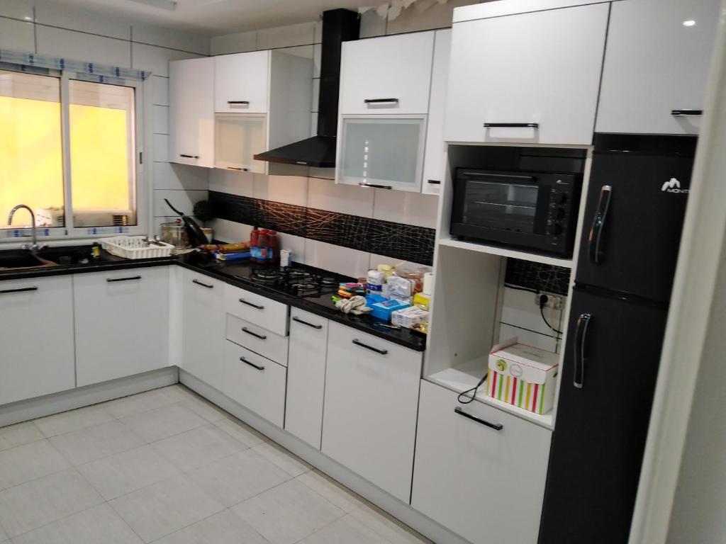cocina con armarios blancos y nevera negra en Pretty and independent Apartment located in Tunis city, en Túnez