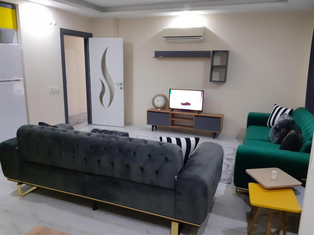a living room with a black couch and a tv at Canan Residance in Demre