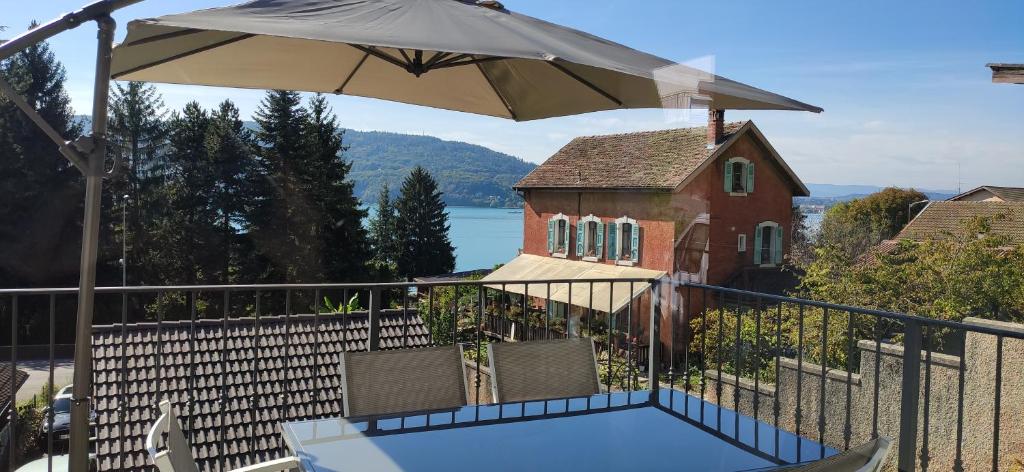 - un balcon avec une table et un parasol dans l'établissement Veyrier du lac petite maison proche d'Annecy, à Veyrier-du-Lac