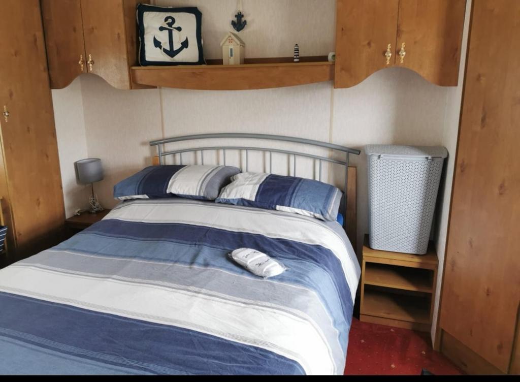 a bedroom with a bed with blue and white sheets at Heacham South Beach static caravan in Heacham