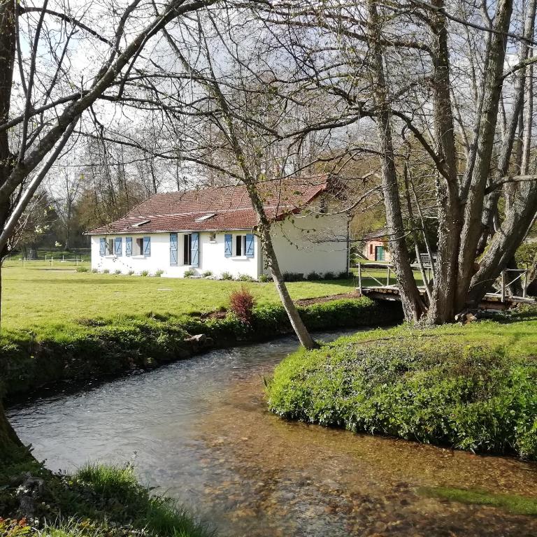une maison blanche avec une rivière devant elle dans l'établissement Au fil de l'eau à la campagne, à Canny-sur-Thérain