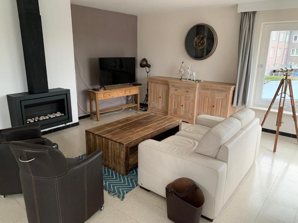 a living room with a white couch and a tv at Vakantie-appartement Lauren XL Westende in Middelkerke