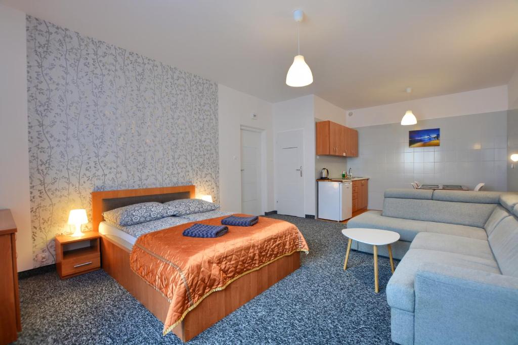 um quarto de hotel com uma cama e um sofá em Apartdom em Krynica-Zdrój