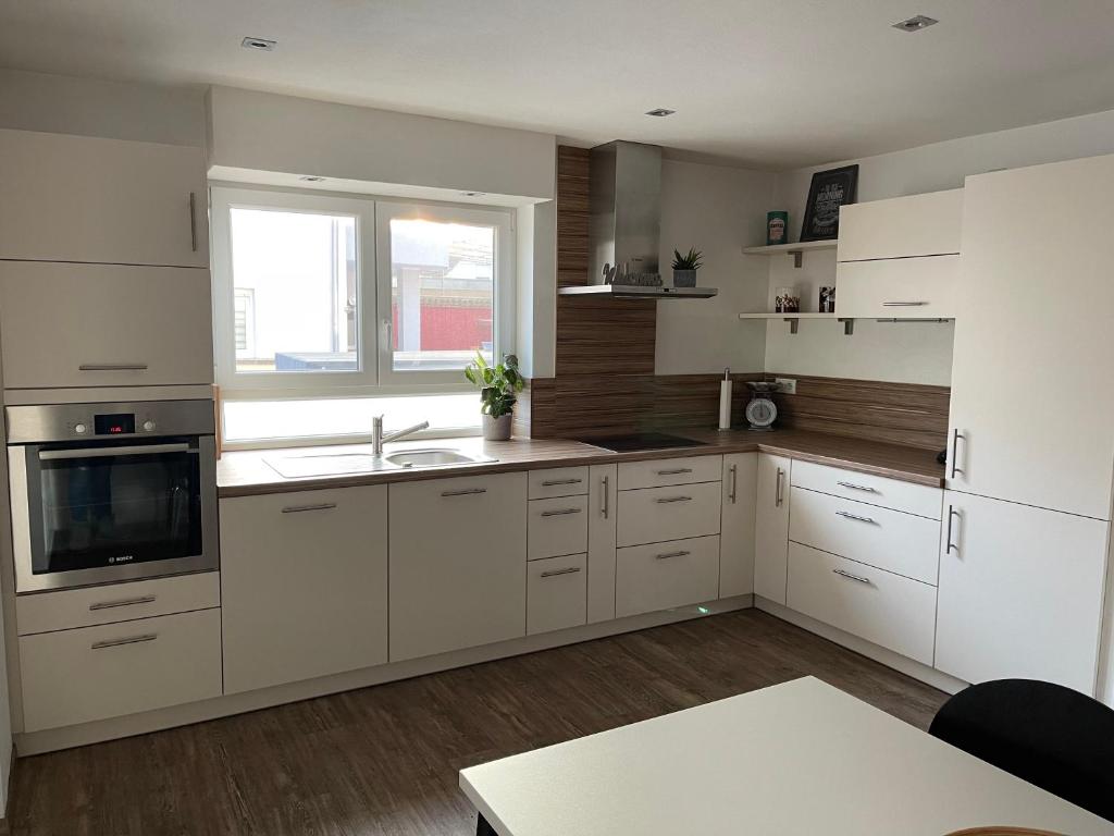 cocina con armarios blancos, fregadero y ventana en Ferienwohnung Jasmin en Neustadt an der Weinstraße