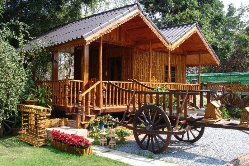 a small wooden cabin with a horse cart in front of it at Home Stay Stc Bed And Breakfast in Udon Thani