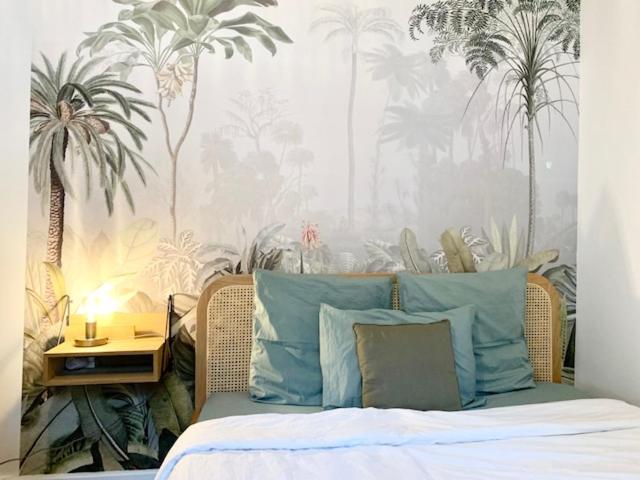 パリにあるコージー スタジオ イン モントルグイユのベッドルーム1室(青い枕とヤシの木のベッド1台付)