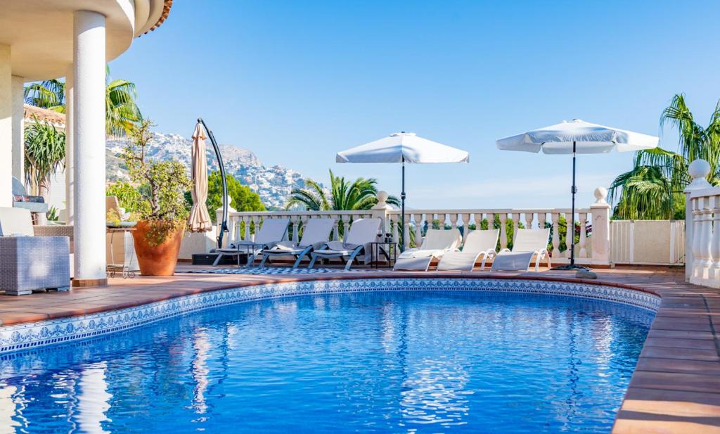 a swimming pool with a blue umbrella on top of it at Guesthouse Villa Altea in Altea