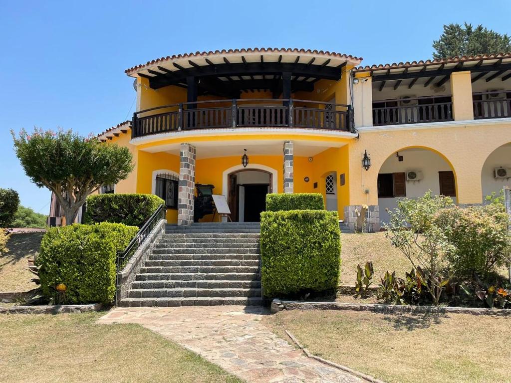 una casa amarilla con escaleras delante en Complejo Turistico - Hotel Pinar serrano - Bialet Masse - Cordoba en Bialet Massé