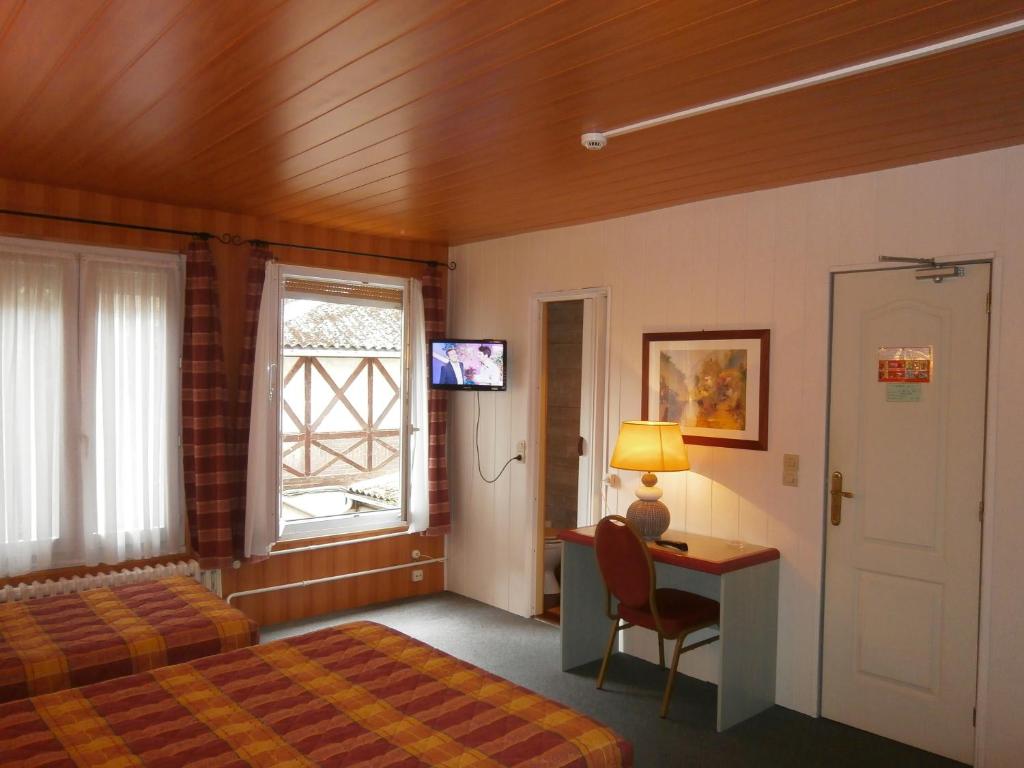 a bedroom with a bed and a desk and a window at Hotel Beausejour in Rouen