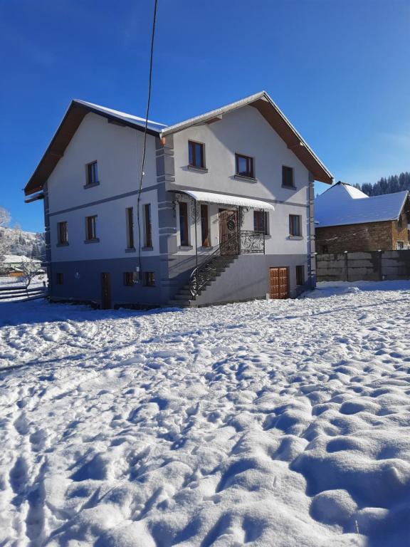 ein Haus im Schnee mit Fußabdrücken im Schnee in der Unterkunft Карпатьські зорі in Werchowyna