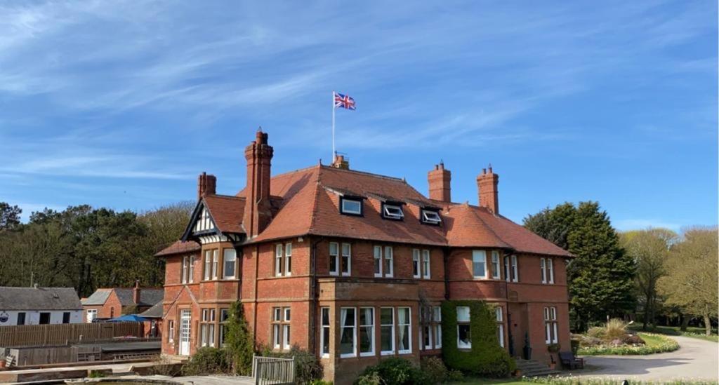 um edifício de tijolos vermelhos com uma bandeira em cima em Sandhill House em Troon