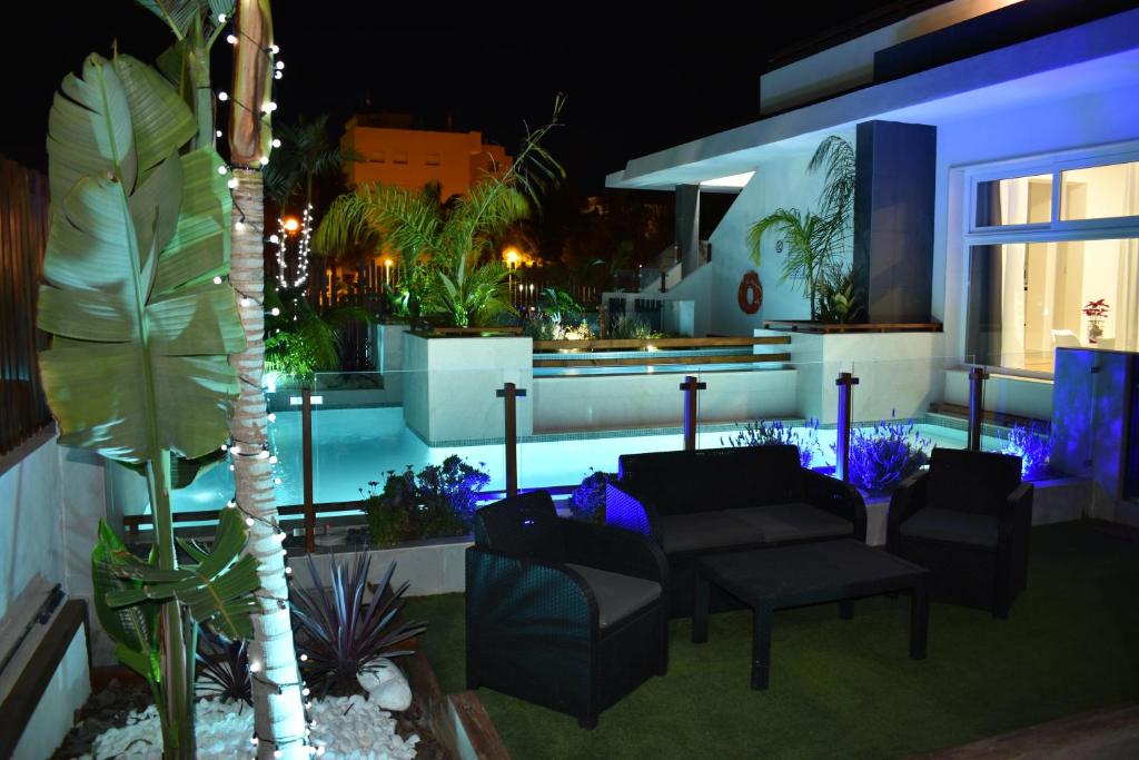 eine Terrasse mit Stühlen und einem Pool in der Nacht in der Unterkunft Alaïa Apartamentos in Playa Paraiso