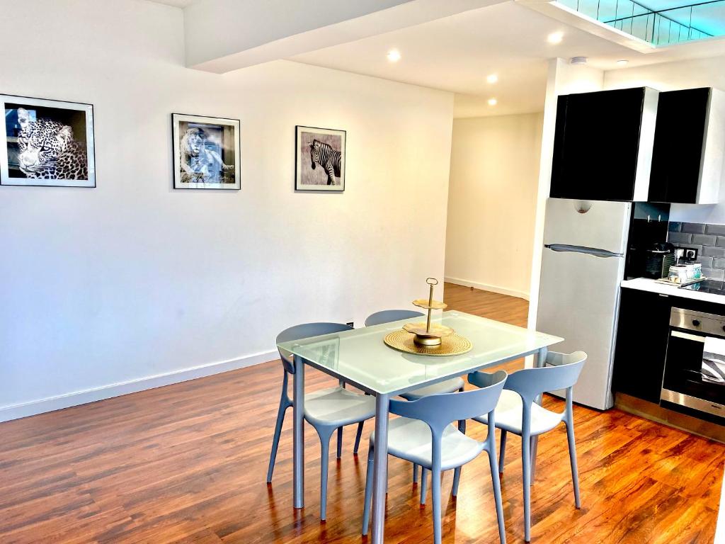 uma sala de jantar com uma mesa de vidro e cadeiras em LE CARDINAL, appartement avec parking privé, gare, centre ville, em Annecy