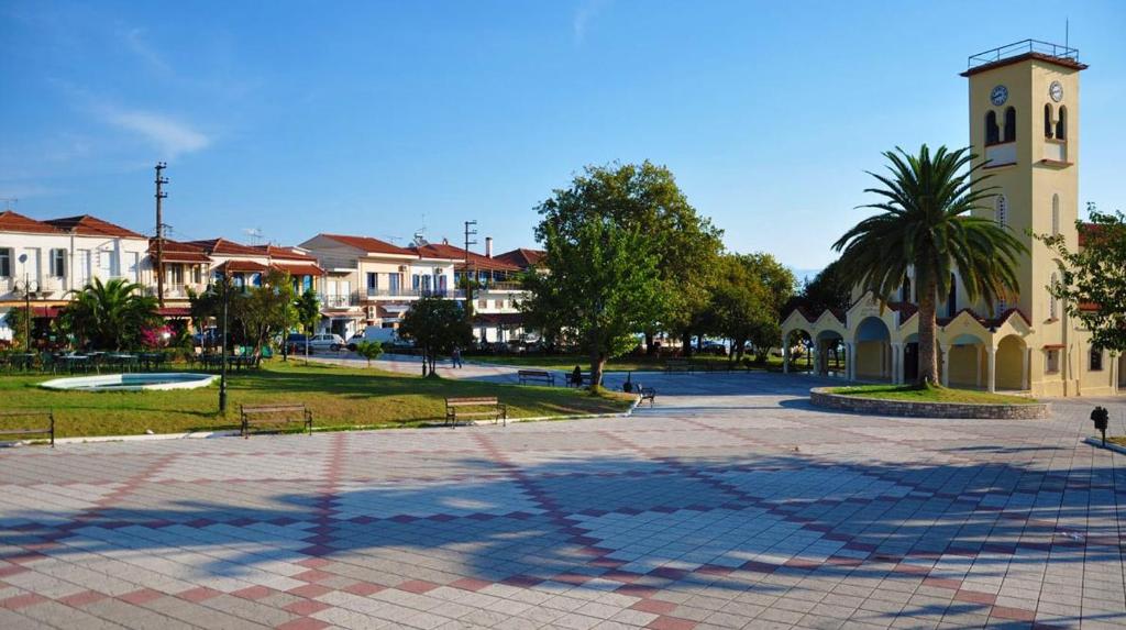 un edificio con una torre de reloj junto a un parque en Petalidi Square, en Petalidi