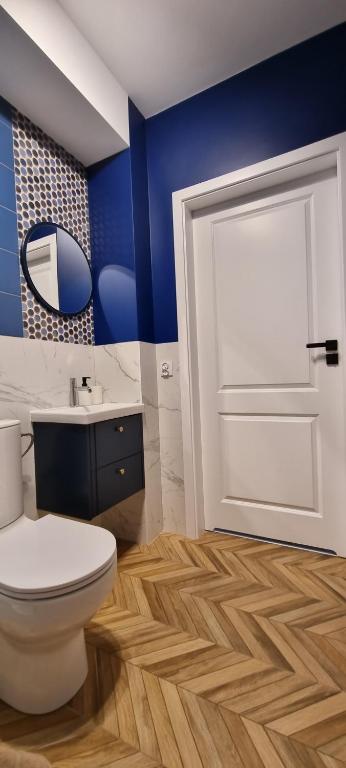 a bathroom with a white toilet and a blue wall at Apartamenty Pastelowe, Suntago, Deepspot, Mszczonów in Mszczonów