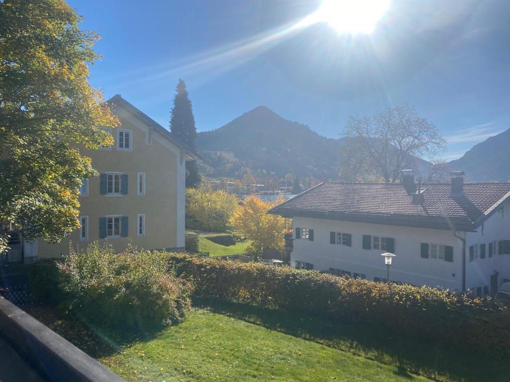 Um par de casas brancas com o sol atrás delas. em Studio Inselblick für 2 mit Traumpanorama em Schliersee