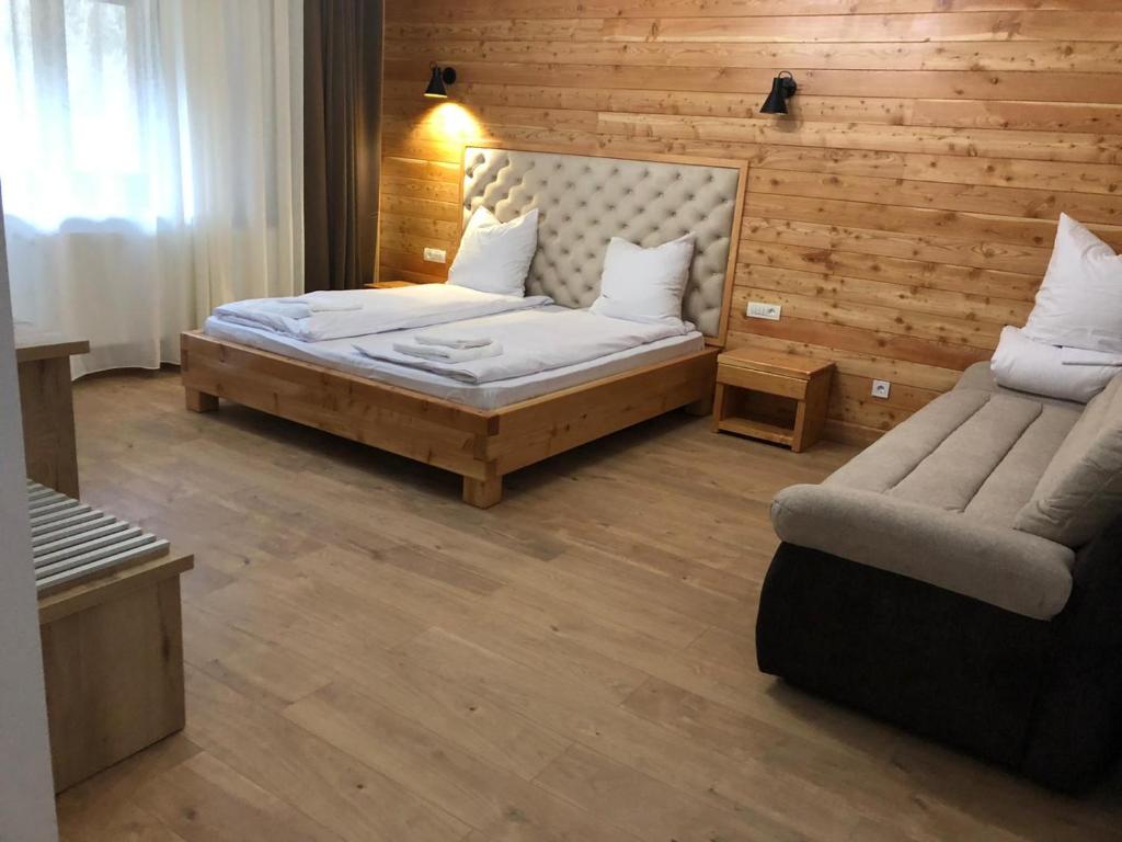 - une chambre avec un lit et un canapé dans l'établissement Pensiunea Armonia Albac, à Albac