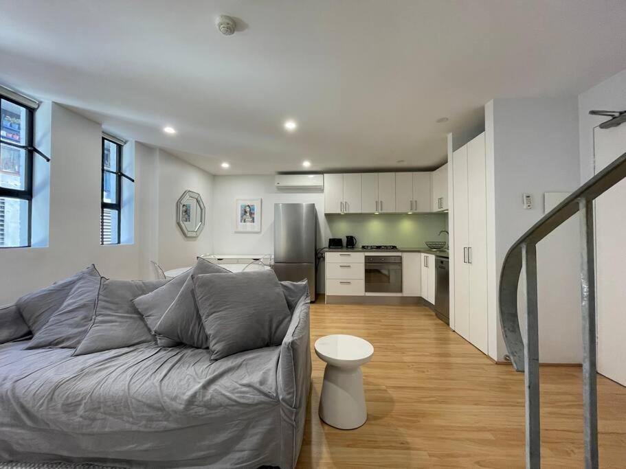 uma sala de estar com um sofá e uma cozinha em Modern 2 Bedroom Warehouse Conversion em Sydney