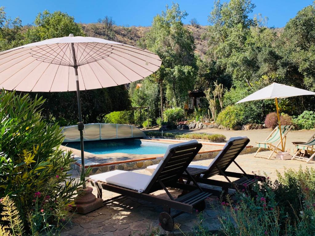 two chairs and an umbrella next to a pool at KURALEMU Casa de Campo in Curacaví