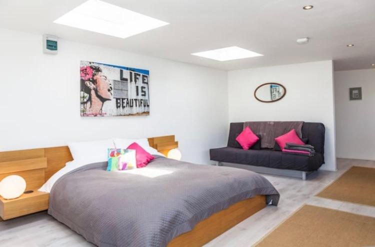a bedroom with a large bed and a couch at The Studio Christchurch B&B Luxury Garden Room in Christchurch