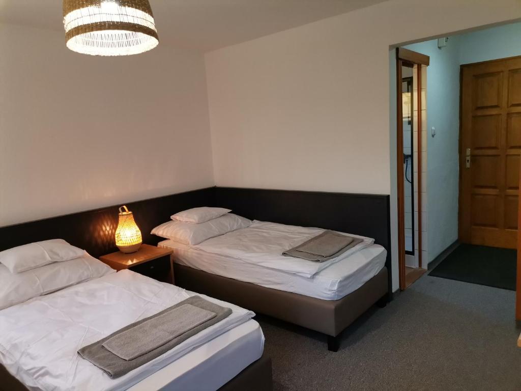 sypialnia z 2 łóżkami, lampką i drzwiami w obiekcie Jonathan Bed&Pizza w mieście Komárom