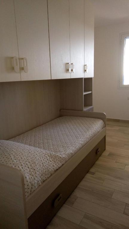 łóżko w pokoju z białymi szafkami w obiekcie STELLA MARIS Sardinia w mieście La Caletta