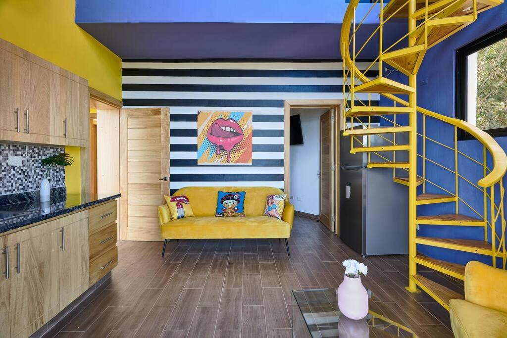 a living room with a yellow couch and a staircase at Villa Favella-Pop-Art-View-7BR-Jamaca De Dios-Balcony-Dream in Jarabacoa