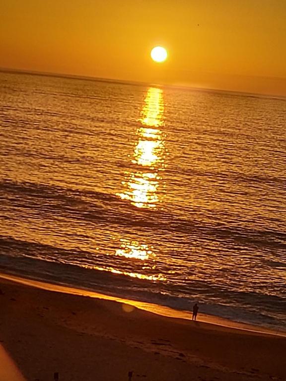 una persona parada en la playa al atardecer en Arenamaris Apartment, en Algarrobo